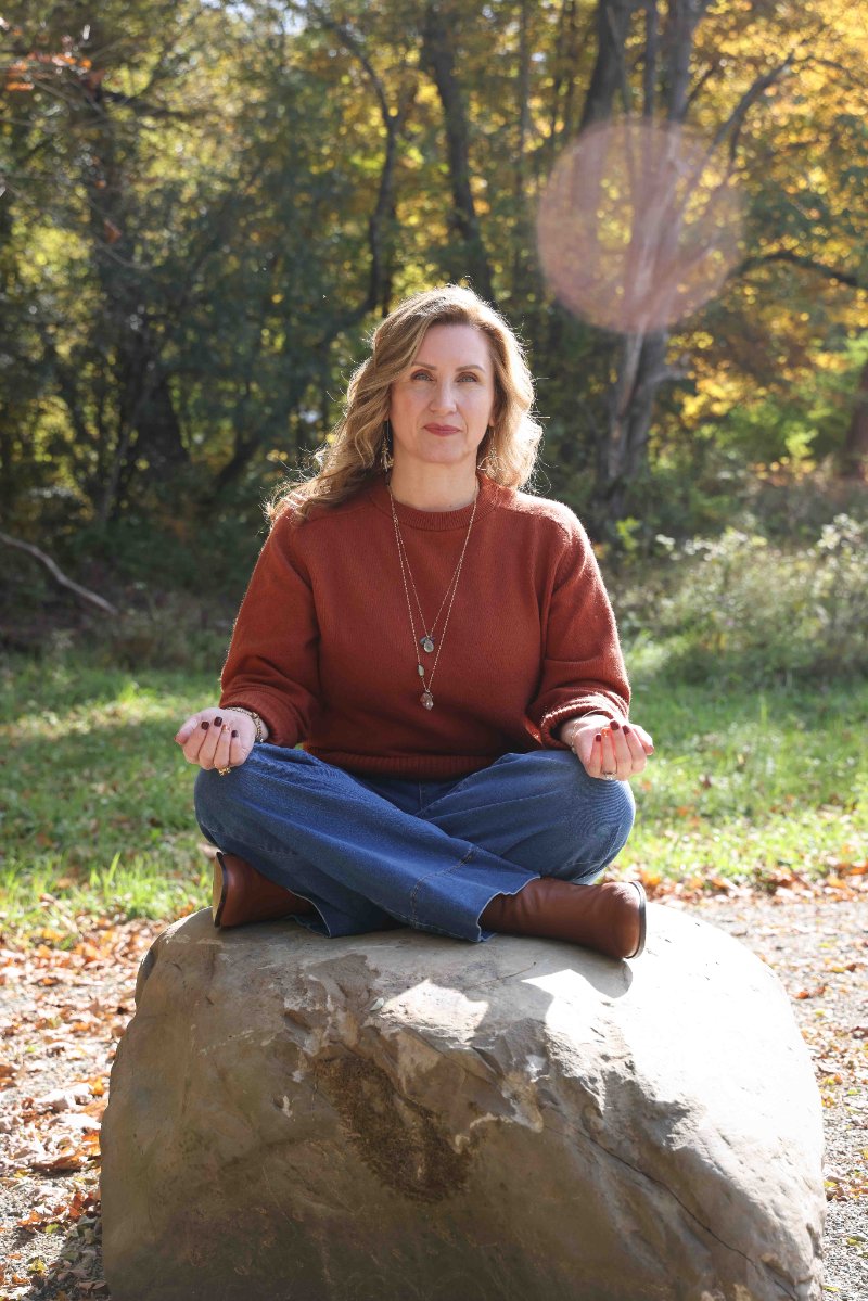 Christine Dorsey seated in meditation on a large stone